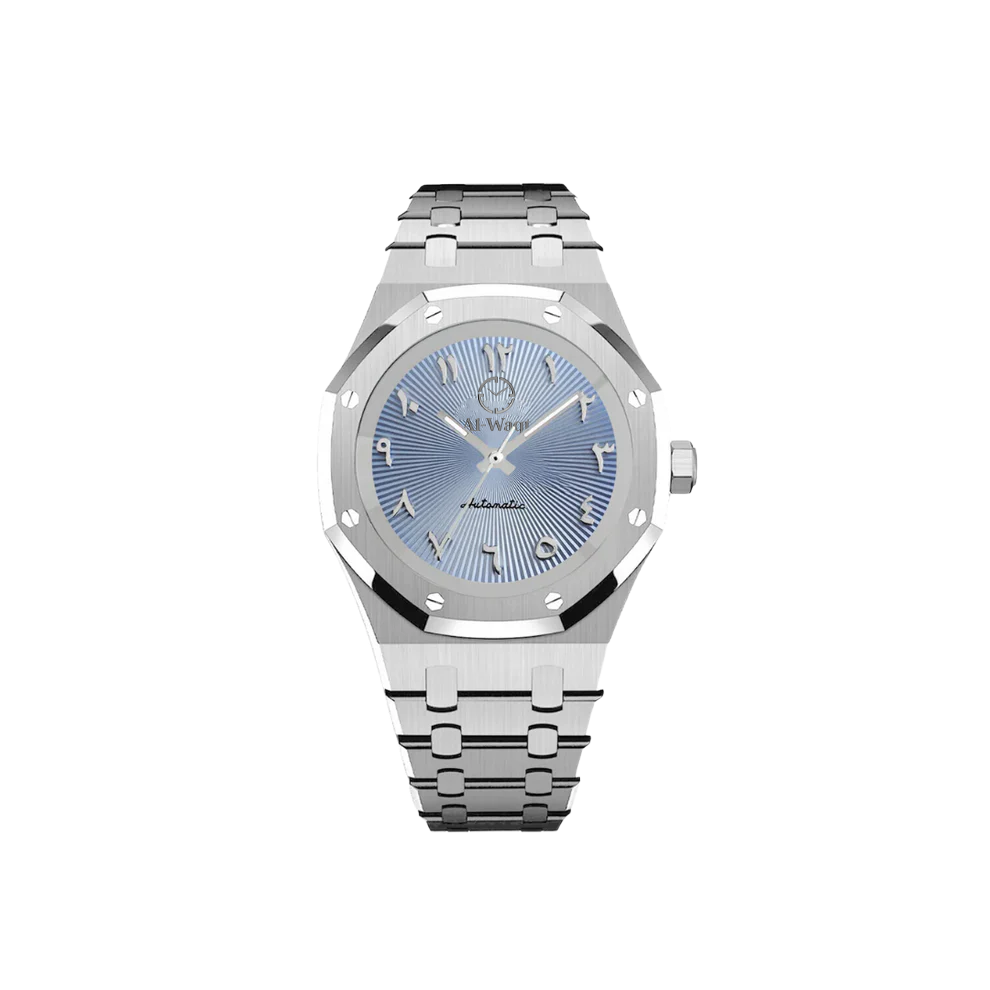 Une montre avec un bracelet argenté et un cadran bleu et des aiguilles argentées. Les chiffres sont arabes et au dessus du centre du cadran se trouve le logo de la marque Al-Waqt.