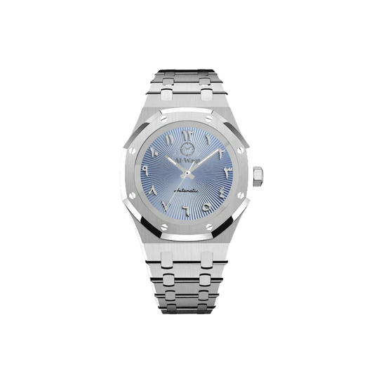 Une montre avec un bracelet argenté et un cadran bleu et des aiguilles argentées. Les chiffres sont arabes et au dessus du centre du cadran se trouve le logo de la marque Al-Waqt.